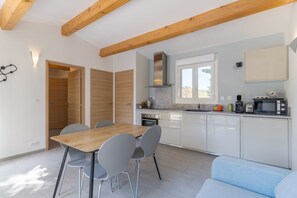 Une cuisine moderne avec une table à manger en bois, des chaises grises et un four encastré.