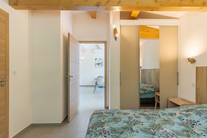 Une chambre à coucher avec un lit, un plafond en bois et une porte donnant sur une autre pièce.