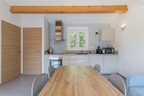 Une cuisine moderne avec une table en bois, des armoires blanches et un four encastré.