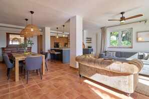 Un vaste espace de vie comprenant un canapé, une table à manger, des chaises et une cuisine à l’arrière-plan.