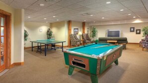A pool table, chairs, a sofa, and a television in a room with carpeted flooring and wooden accents. - WorldMark Galena 2br (Galena)