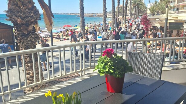 Un balcone con vista su una spiaggia, palme e una folla.