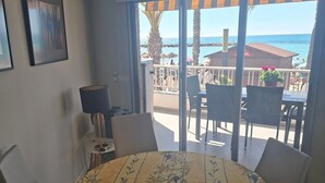 Un tavolo rotondo con tovaglia floreale, quattro sedie, una lampada e vista mare da un balcone.