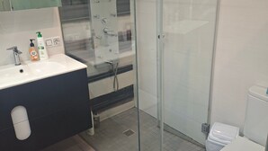 Un bagno moderno con cabina doccia in vetro, lavandino bianco e water.