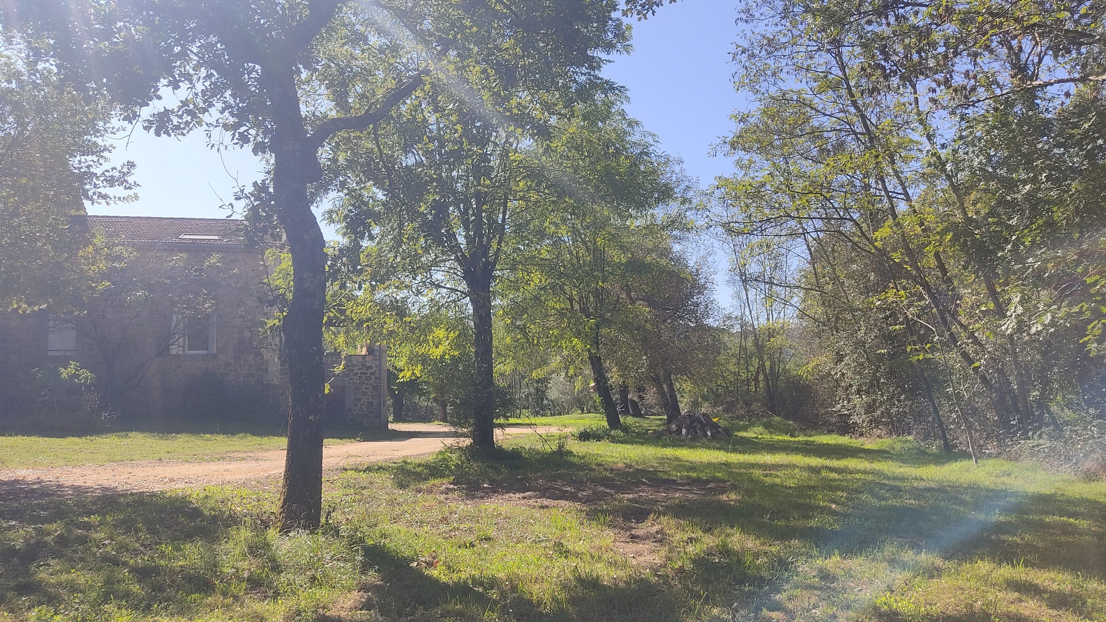 A rustic building surrounded by trees and a dirt path.