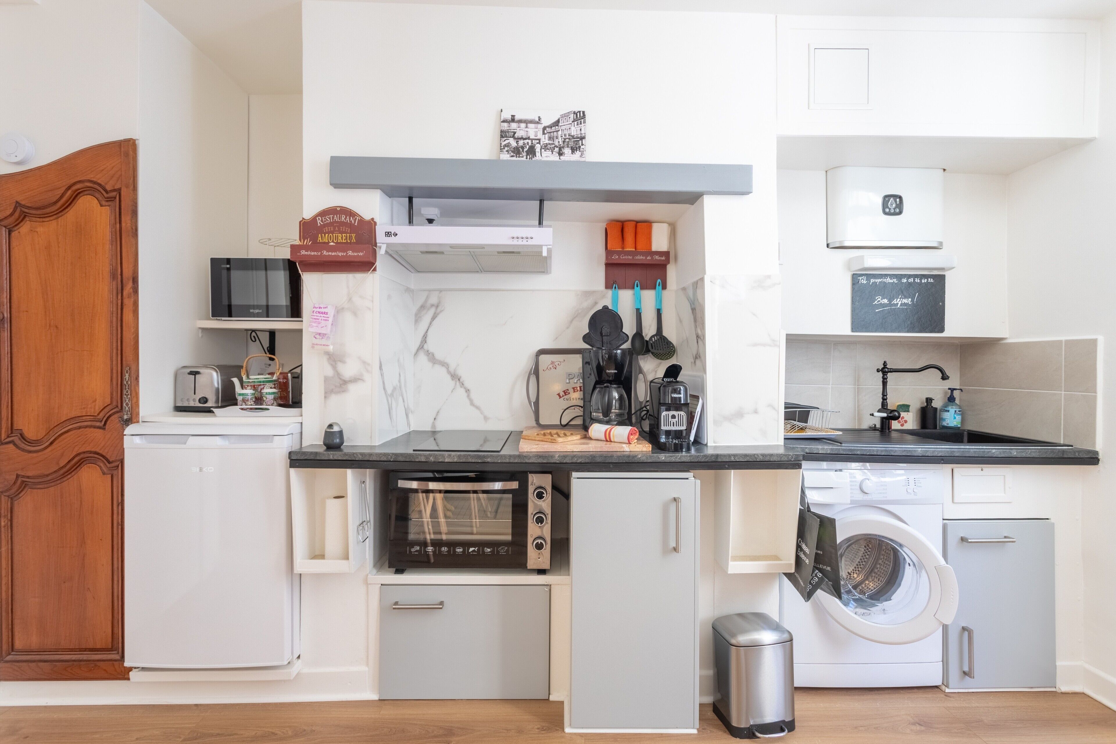 A compact kitchen with a microwave, toaster, oven, and washing machine.