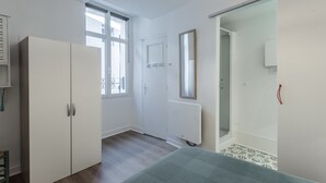 A bedroom with a bed, wardrobe, window, and a door leading to a bathroom. - Apartment 'T2 Océane' with Wi-Fi (Salies-de-Béarn)