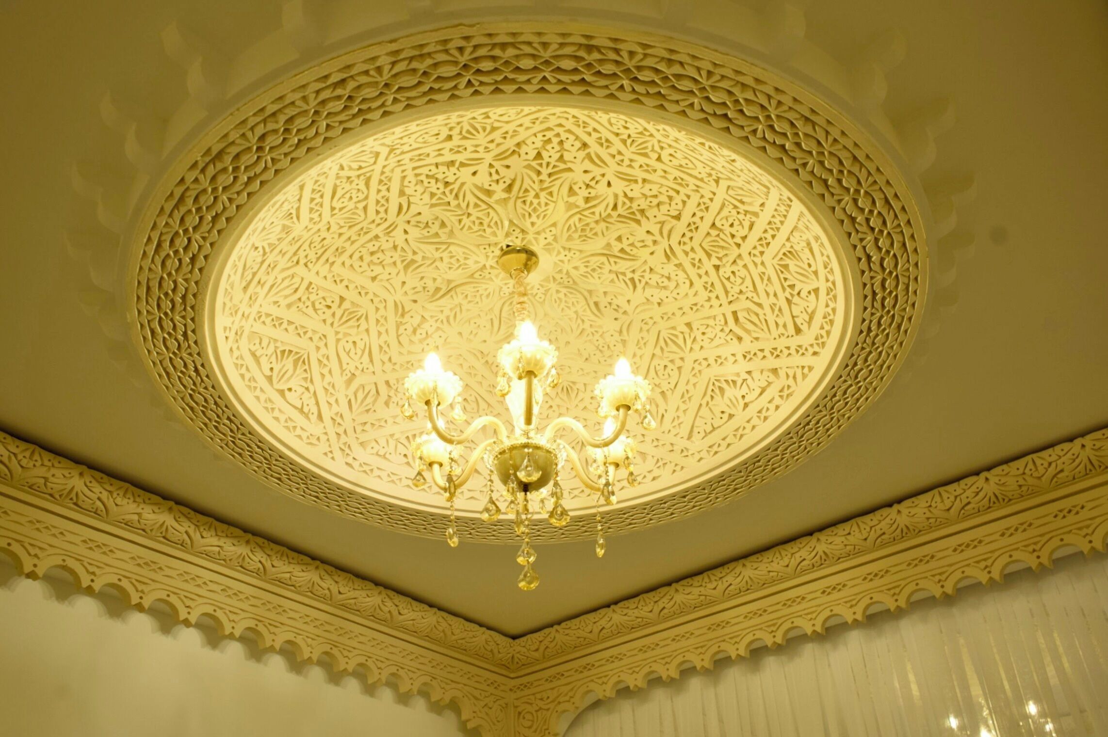 Un plafond richement décoré de motifs complexes et un lustre.