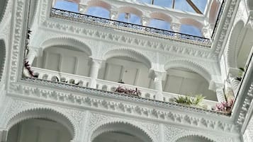 Ein mehrgeschossiges Atrium mit aufwendigen weißen Bögen und einem Oberlicht.