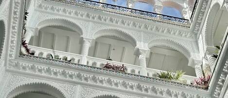 Un atrio de varios niveles con arcos blancos ornamentados y una claraboya.