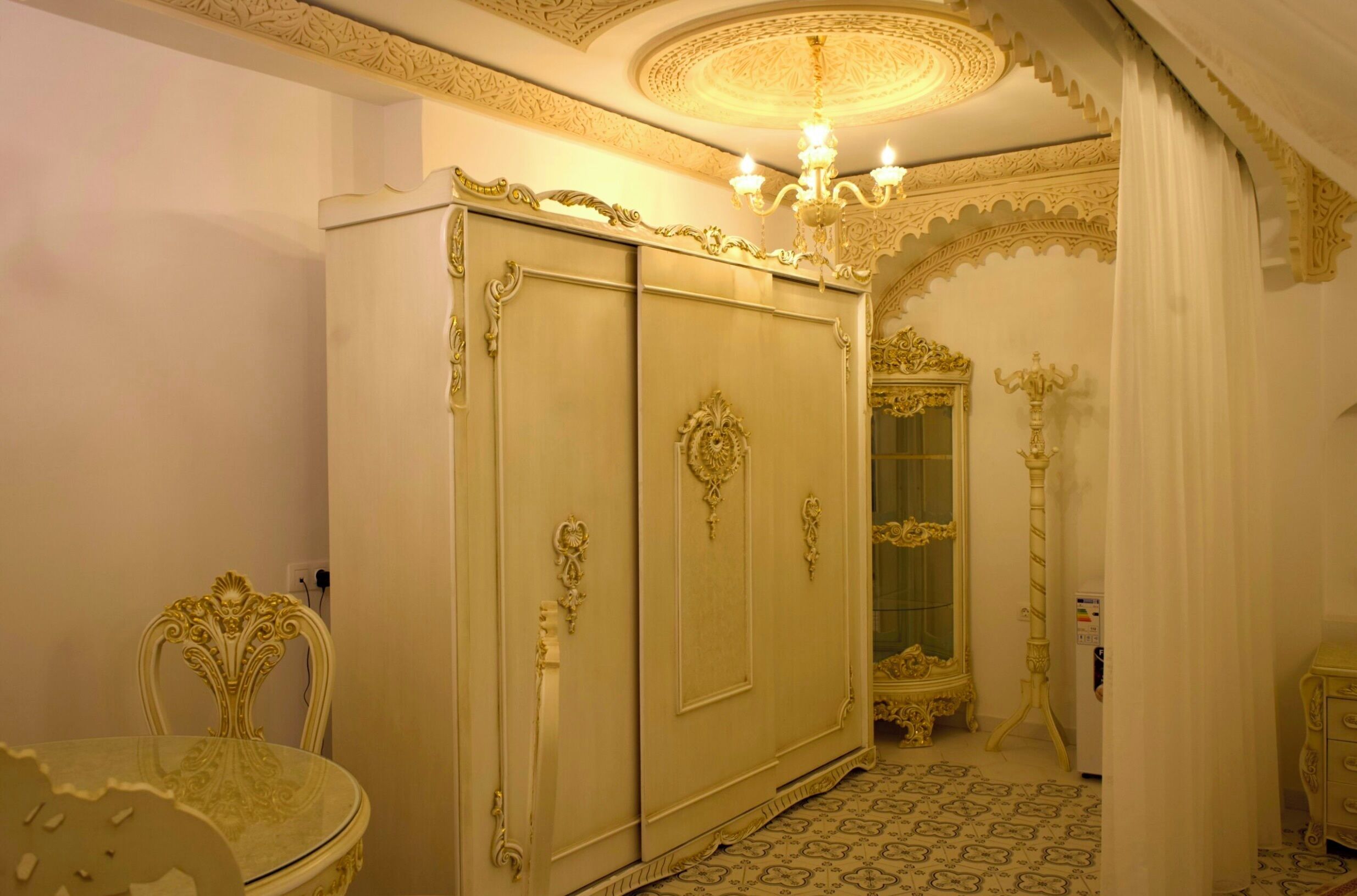 A room with ornate furniture, a chandelier, and a patterned floor.