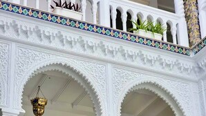 A multi-level balcony with ornate white railings and arches, potted plants, and a hanging light fixture. - Dar Lala Fatma (Algiers)