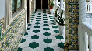 A corridor with white walls, green and white patterned flooring, and ornate white columns. - Dar Lala Fatma (Algiers)