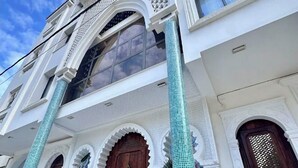A building with ornate arches, a wooden door, and tiled columns. - Dar Lala Fatma (Algiers)