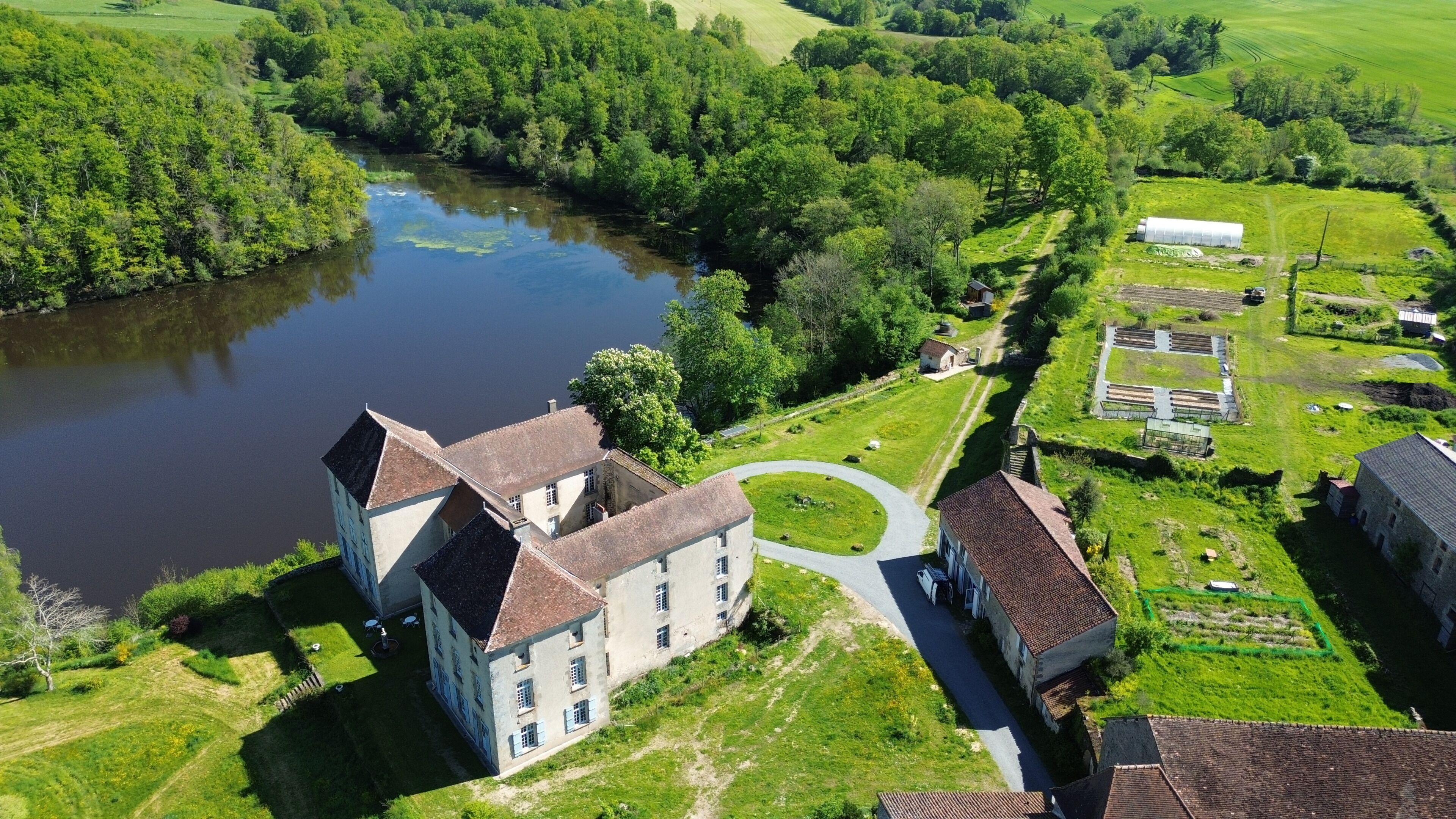 Un'ampia tenuta con un fiume, una strada sinuosa e diversi edifici.