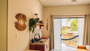 Una cocina moderna con una isla integrada, comedor y puerta corrediza de vidrio que da a un balcón con hamaca.