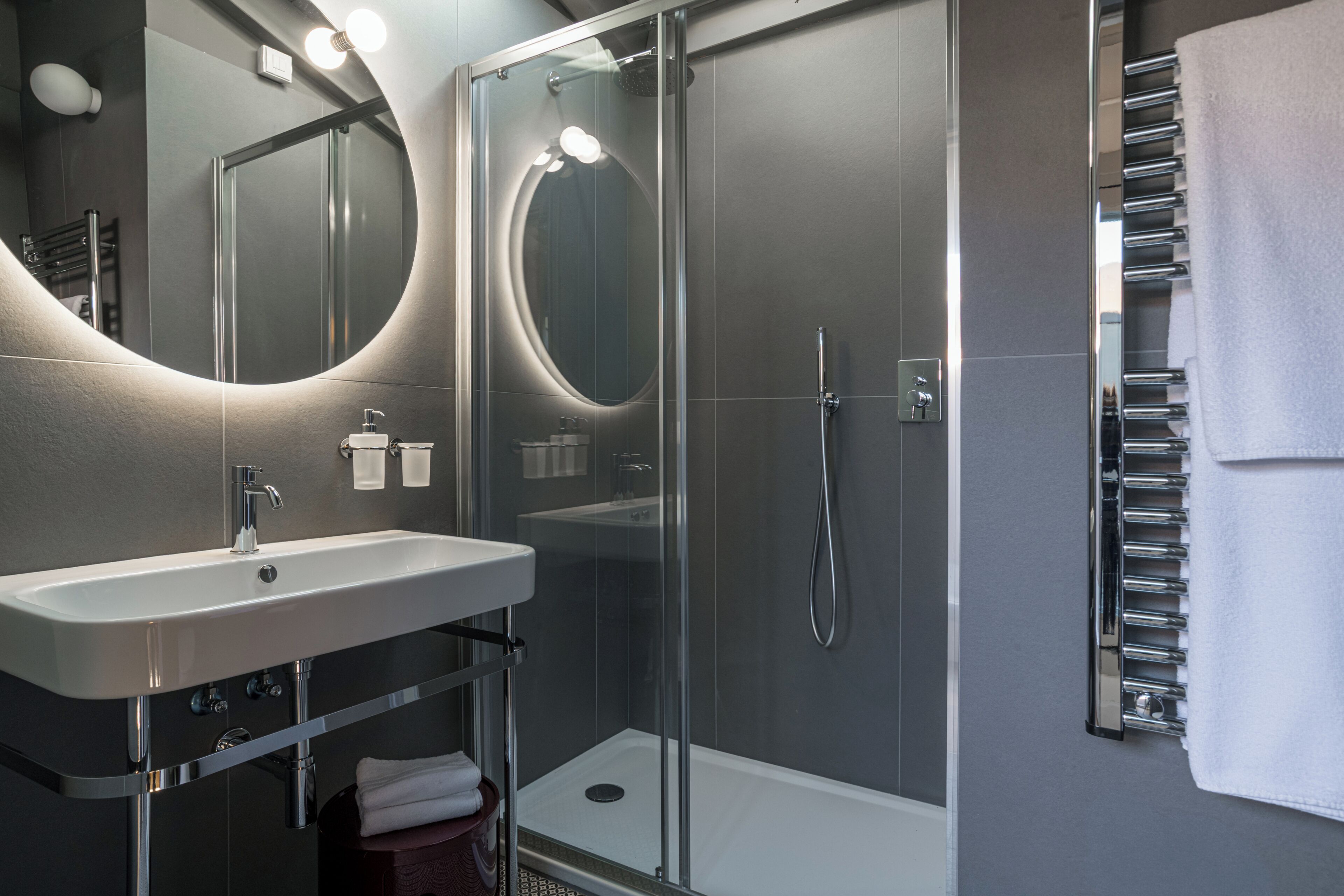 A modern bathroom with a glass-enclosed shower, a sink with chrome fixtures, and a towel rack.