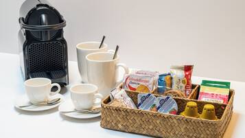 Un plateau de petit-déjeuner comprenant une machine à café, des tasses, un panier rempli de divers aliments et des condiments.