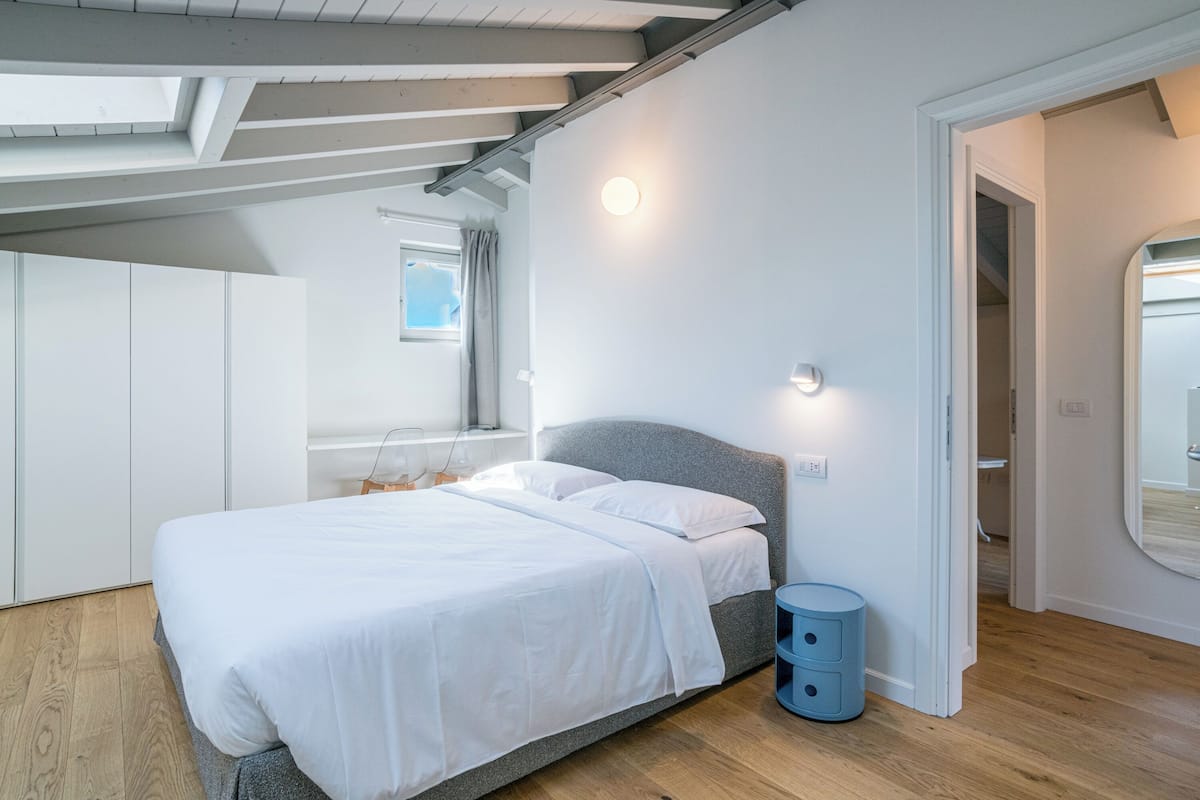 Un dormitorio con cama, mesita de noche, armario y espejo.