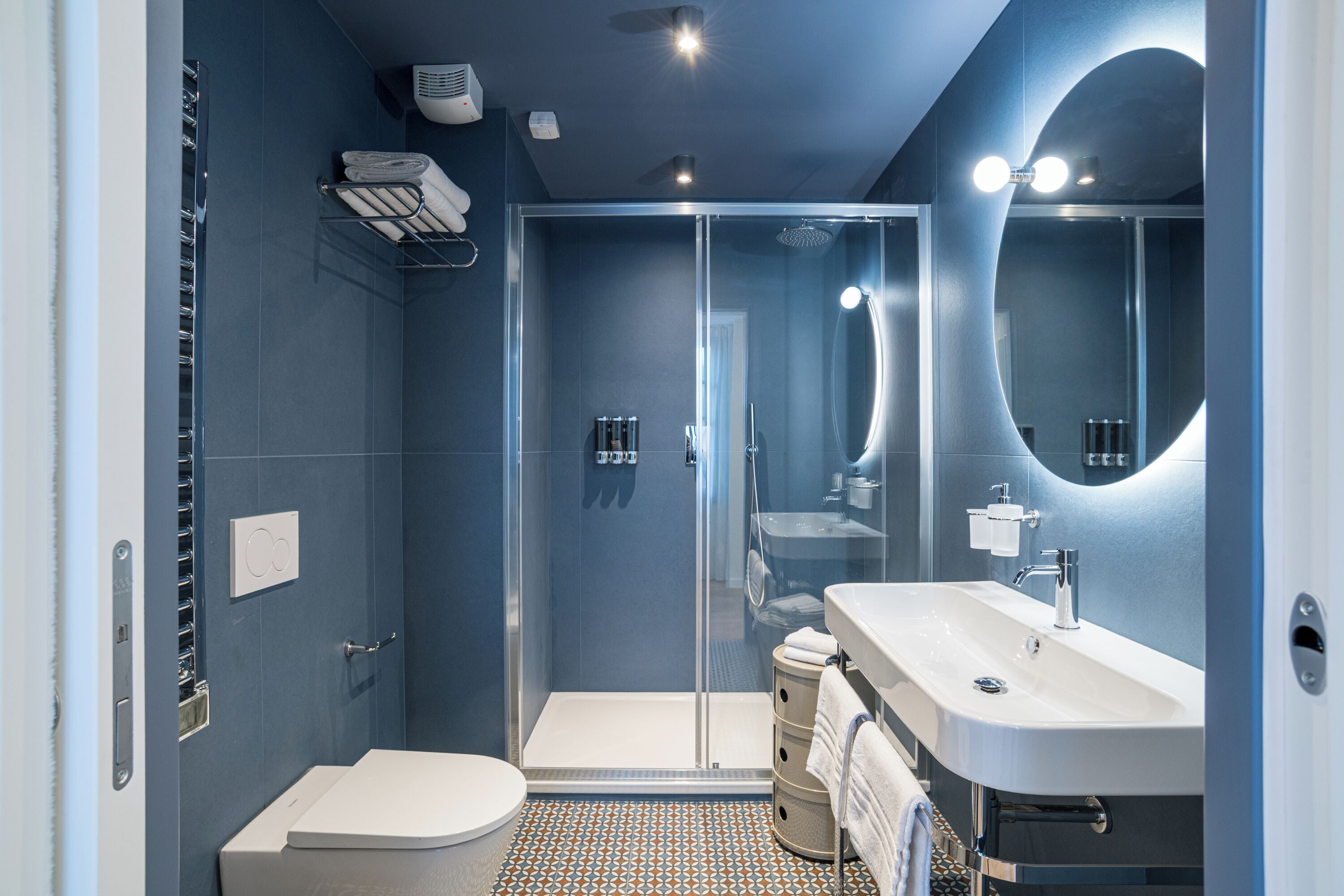 A modern bathroom with a shower, toilet, and sink, featuring a blue color scheme and contemporary design.