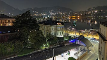 A nighttime view of a waterfront cityscape with buildings, a train station, and a body of water reflecting lights.