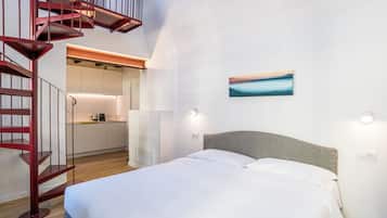A bedroom with a bed, a staircase, and a kitchen area.