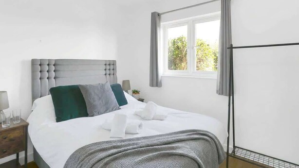 Una camera d'albergo con un letto, un comodino, una finestra con tende e vista sul verde.