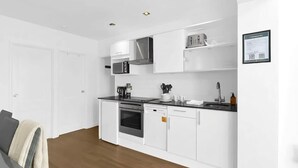 Una cucina moderna con mobili bianchi, un forno a microonde, un fornello e una lavastoviglie.