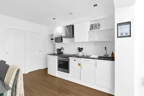 Una cocina moderna con armarios blancos, microondas, estufa y lavavajillas.