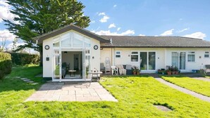 Una casa a due piani con un patio, un ingresso e un piccolo giardino.