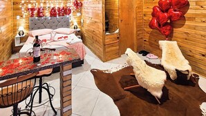 Interior acogedor de una cabaña de madera, con una cama, una mesa de comedor y una chimenea.