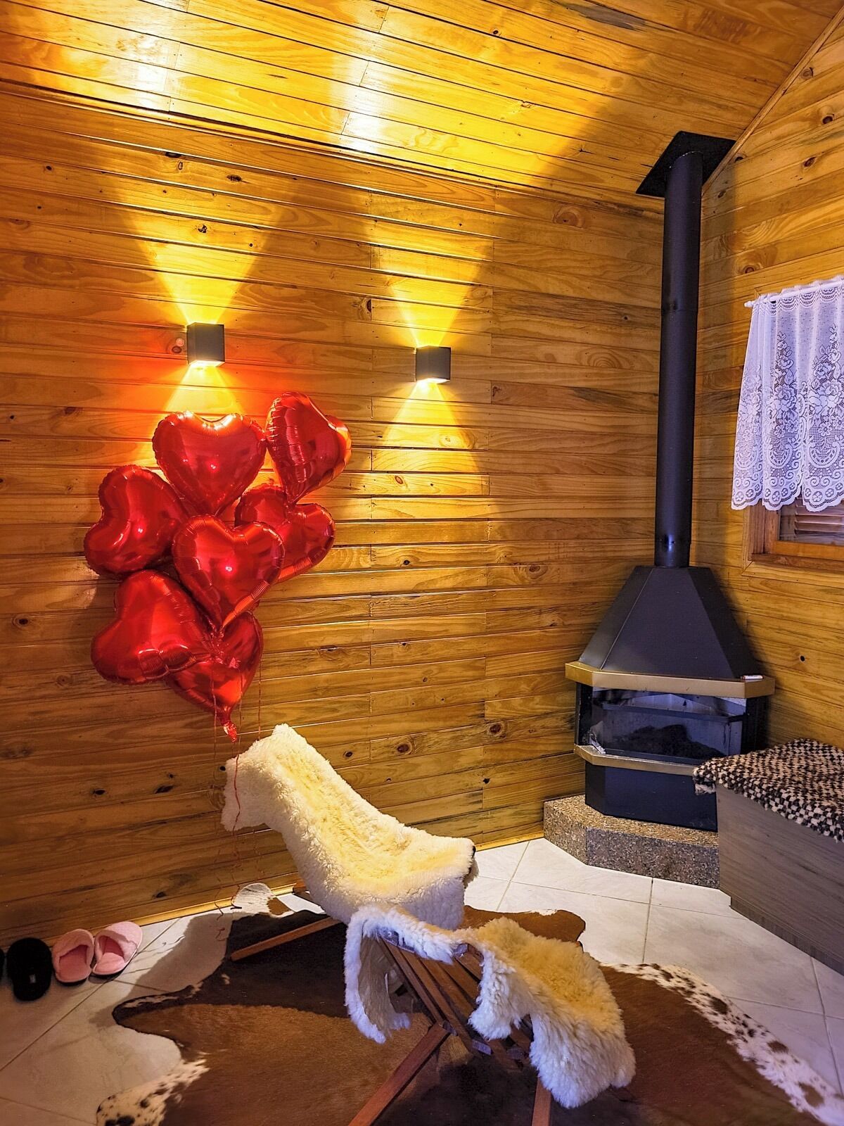 A cozy cabin interior with wooden walls, a fireplace, and heart-shaped balloons.