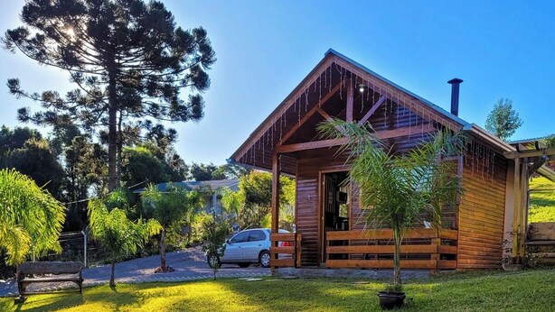Una cabaña de madera con un hogar a leña de ladrillo y troncos de madera en el jardín.