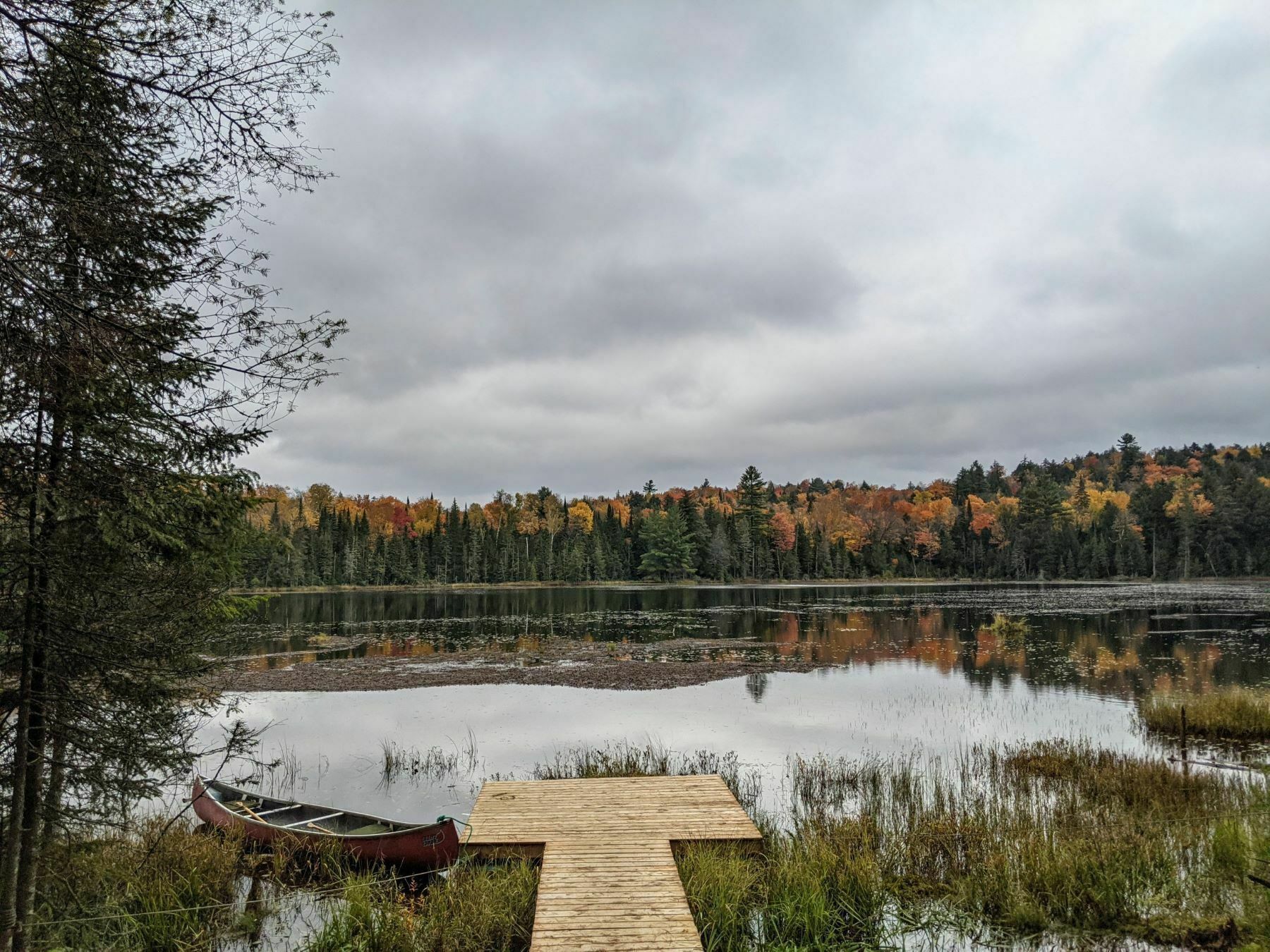Ein ruhiger See mit einer Holzsteganlage und einem Kanu.