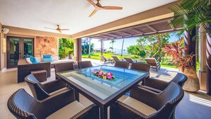 A modern outdoor dining area with wicker furniture, a glass-top table, and ceiling fans. - Ground Floor Punta Mita Condo with Shared Pool (Punta Mita)