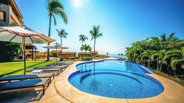 A resort pool with lounge chairs, umbrellas, and palm trees. - Ground Floor Punta Mita Condo with Shared Pool (Punta Mita)