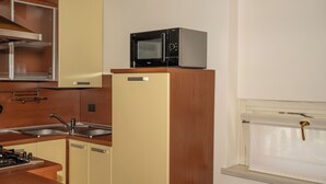 Una cocina con un microondas sobre un mueble, un fregadero y una estufa.