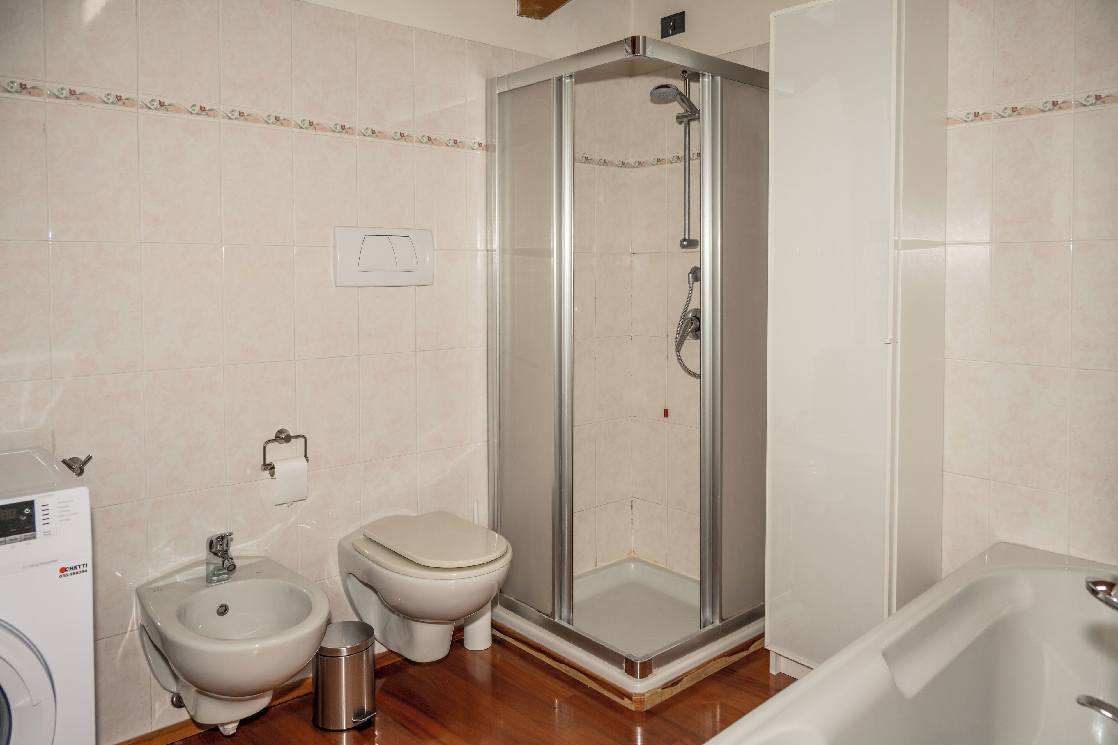 Un baño con ducha, inodoro, bidé y lavadora.
