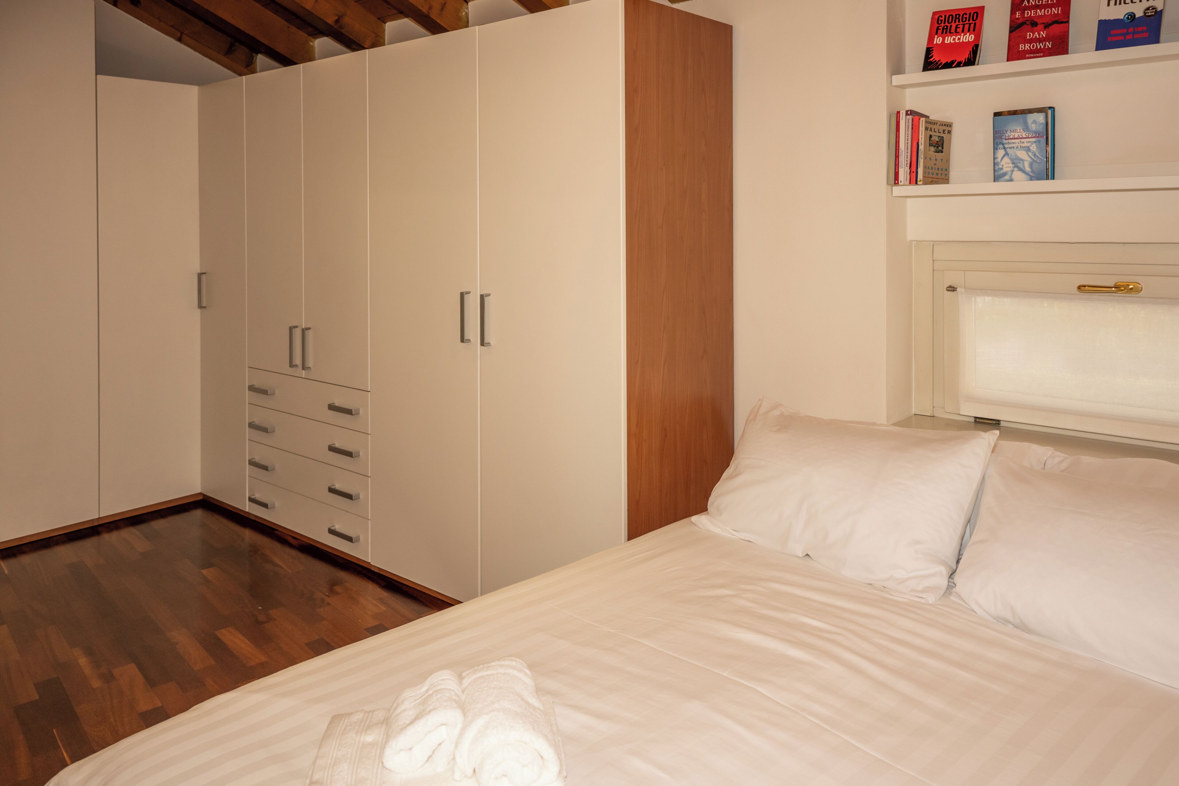 A bedroom with a bed, a wardrobe, and a bookshelf.