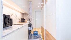 Een moderne keuken met een inbouw vaatwasser, een koffieapparaat en een spoelbak.
