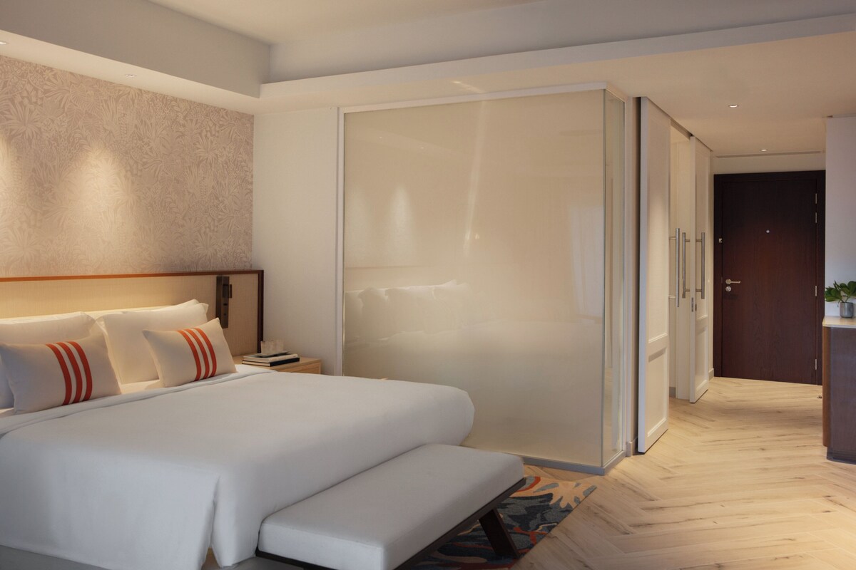Een moderne hotelkamer met een groot bed, een inloopkast en een houten vloer.