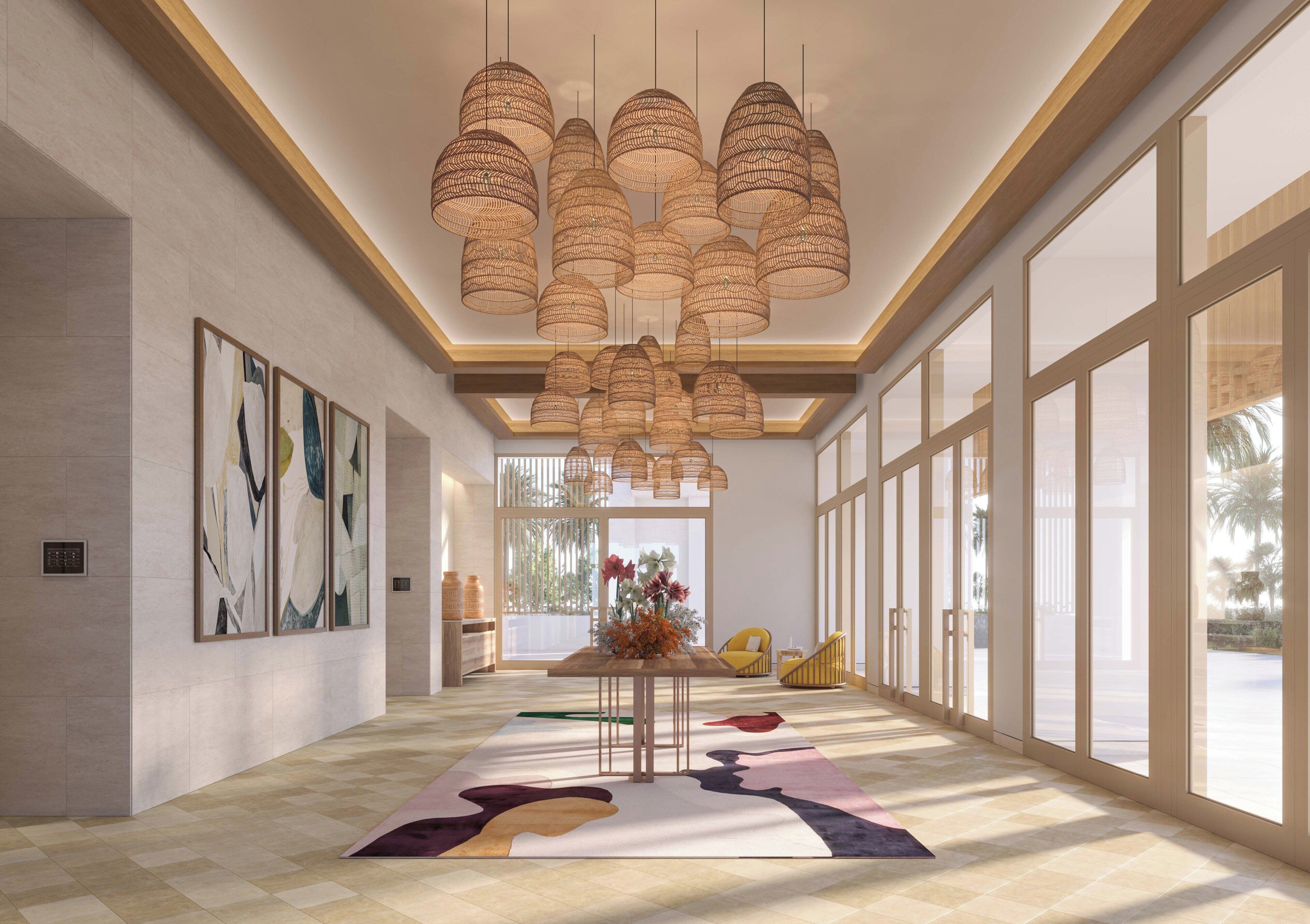 A spacious lobby with a high ceiling, large windows, and a central table with a floral arrangement.