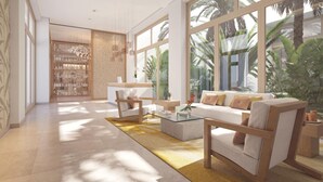 Eine moderne Lobby mit Empfangstresen, Sitzgelegenheiten und großen Fenstern mit Blick auf eine tropische Landschaft.