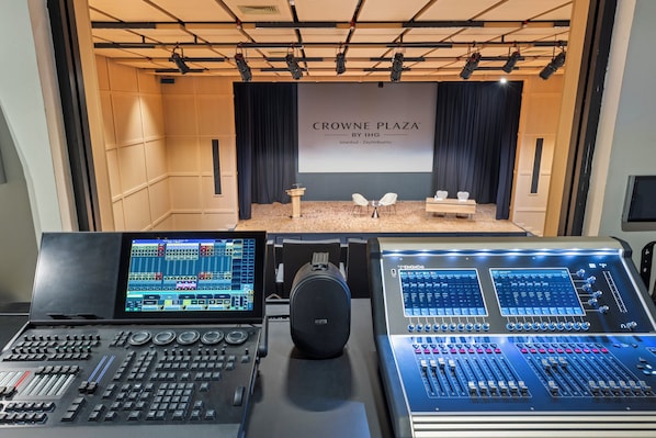 A control room with audio mixing consoles, a stage with a screen displaying 'CROWNE PLAZA BY IHG Istanbul - Zeytinburnu', and a seating area with tables and chairs. - Crowne Plaza Istanbul Zeytinburnu By Ihg (Istanbul)