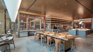 Ein modernes Restaurant mit einer zentralen Bar, verschiedenen Sitzgelegenheiten und zahlreichen dekorativen Elementen.