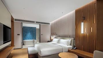 A modern hotel room with a large bed, a bedside table, a TV, and a bathroom with a shower and a blue-tiled wall.