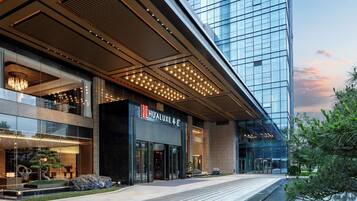 A modern hotel with a glass facade, a prominent entrance, and a well-lit lobby area.