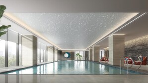 A modern indoor pool with a clear view of the cityscape through large windows. - Hualuxe Guiyang Financial City (Guiyang)