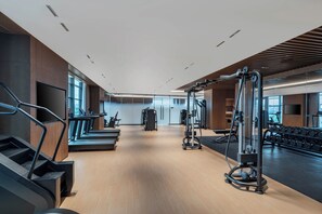 Ein modernes Fitnessstudio mit Laufbändern, Kraftgeräten und Kurzhanteln.