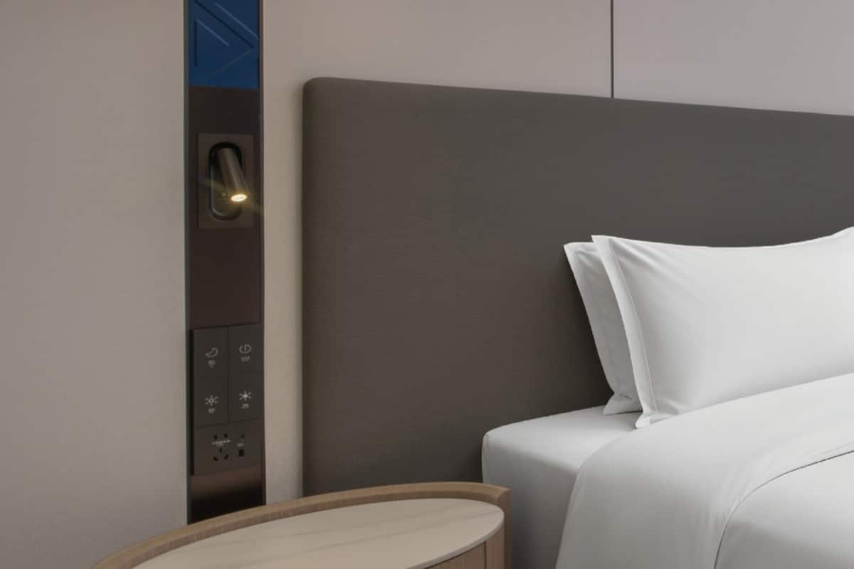 Ein modernes Hotelzimmer mit einem Bett, einem Nachttisch und einer Bedienanlage für die Zimmereinrichtungen.